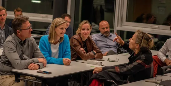 EMBA participants in discussion around tables during a class session