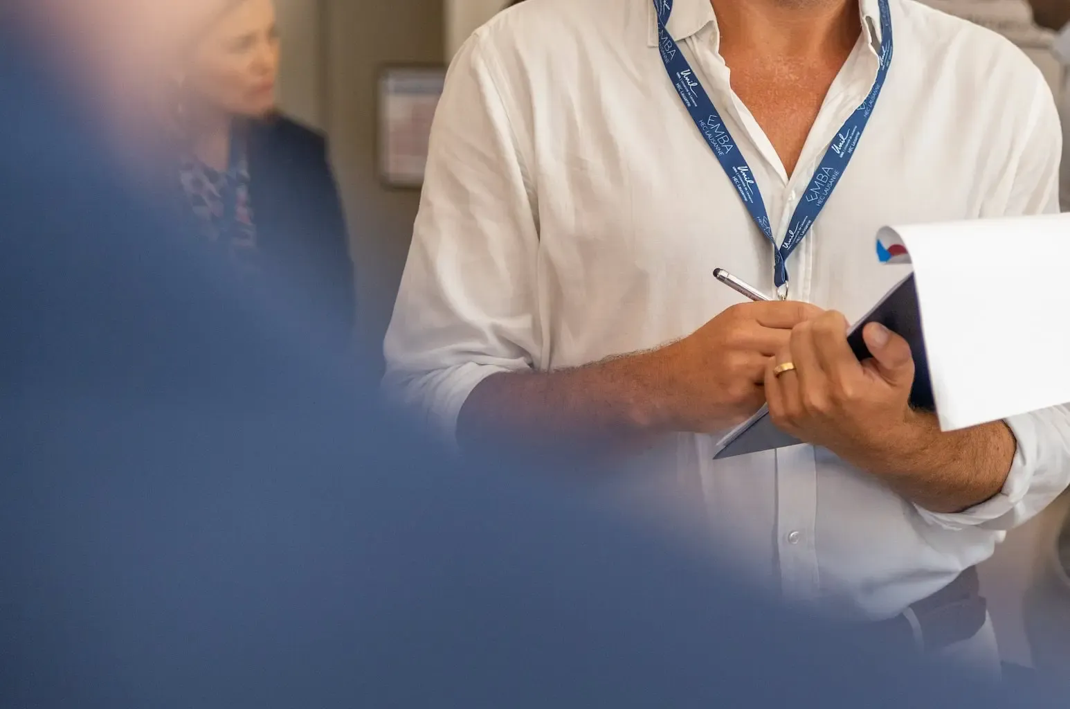A person holding an HEC Lausanne Executive MBA brochure and a pen