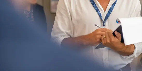 Une personne tenant une brochure de l’Executive MBA HEC Lausanne et un stylo
