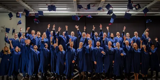 The EMBA Class of 2019 throwing their caps in the air at graduation